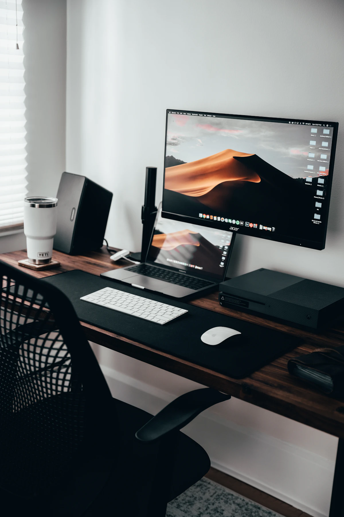 A home workspace with a laptop and monitor on a wooden desk